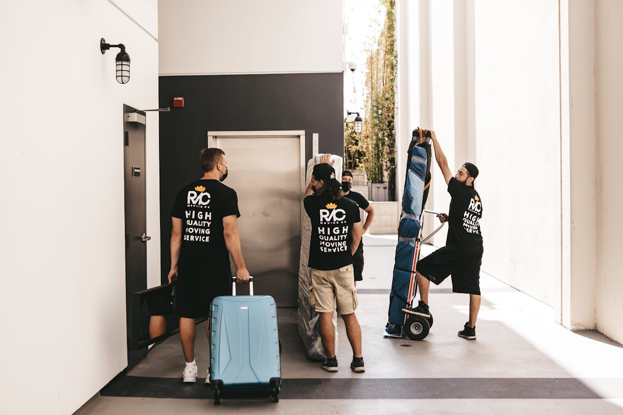 Professional movers transport luggage through an indoor location, showcasing teamwork and efficiency.