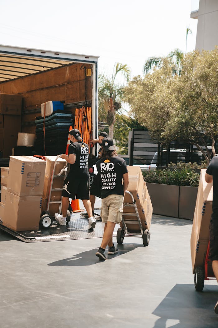 Movers loading boxes into a truck on a sunny day, capturing a busy urban scene.